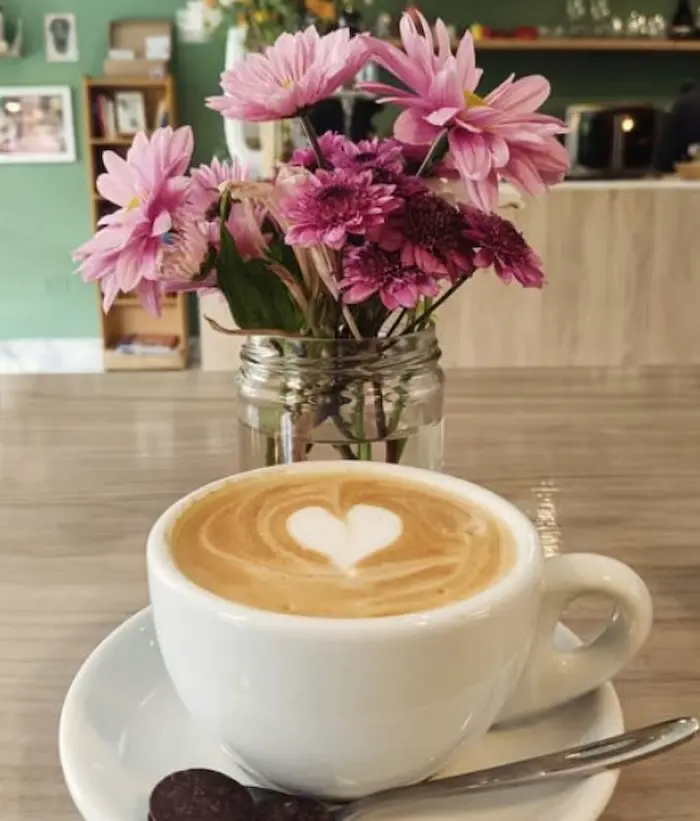 taza de cafe con diseño y un lindo florero atras