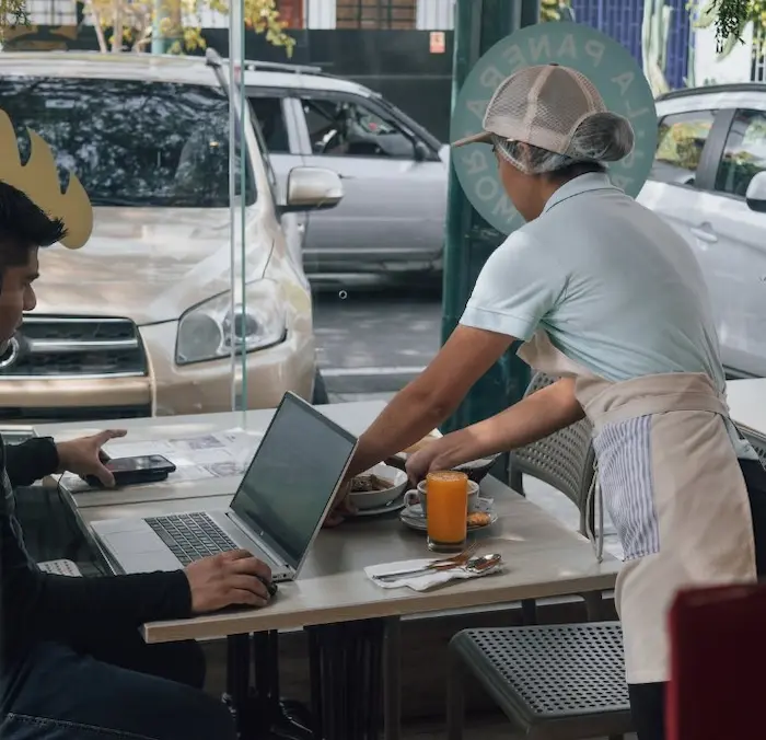 chica atendiendo a su cliente dandole su pedido mientras él trabaja 