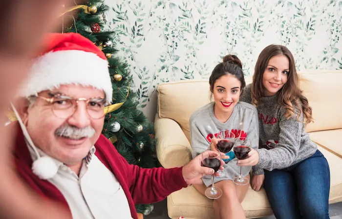 familia realizando actividades de navidad, donde el abuelo tomandose una foto navideña con su hija y nieta